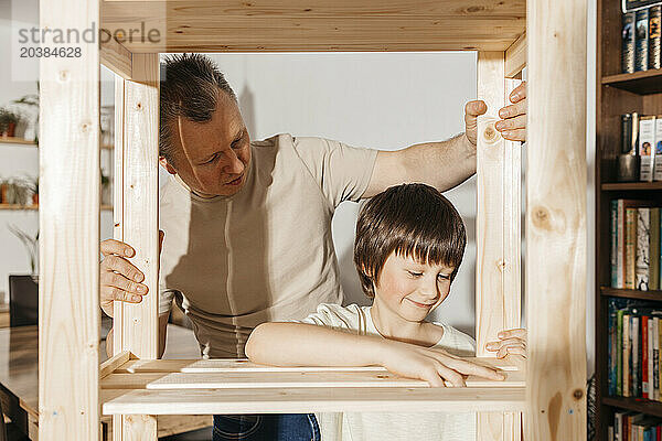 Father and son assembling wooden rack together at home