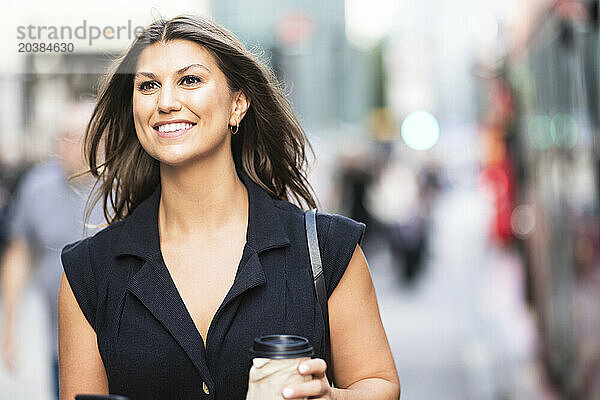 Smiling young woman holding coffee cup