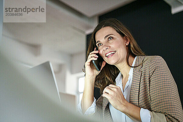 Smiling businesswoman talking on mobile phone in office