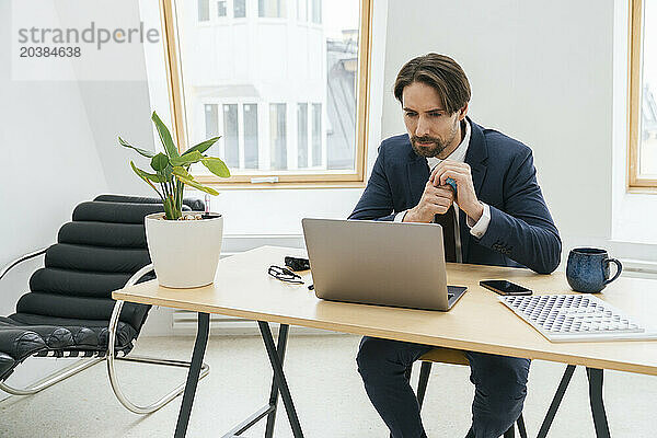 Businessman with globe using laptop at desk in office