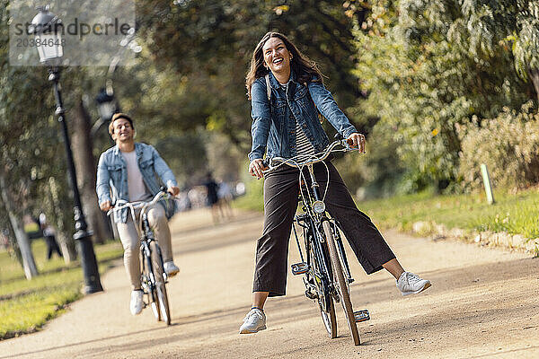 Carefree woman cycling with boyfriend at park