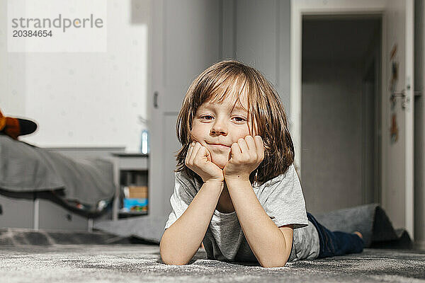 Boy lying on carpet at home