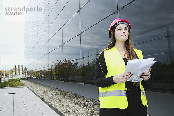 Young geodisist with documents near building