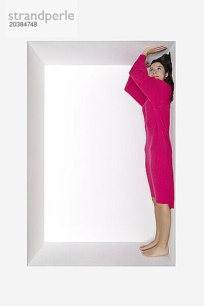 Teenage girl wearing pink dress standing in alcove