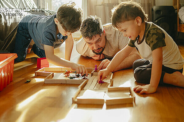 Siblings playing with toys near father at home