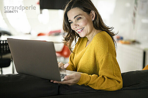 Smiling creative businesswoman using laptop in office