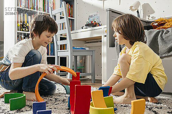 Brothers playing with wooden multi colored toys at home