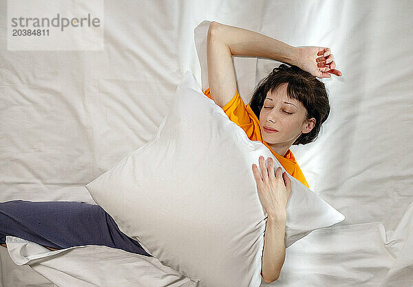 Woman with pillow sleeping on bed at home