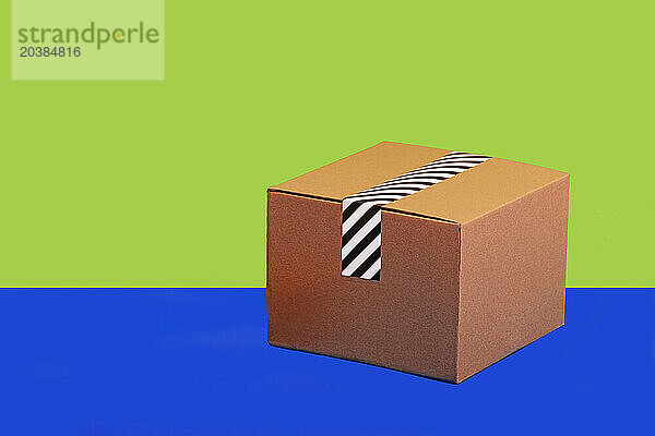 Taped cardboard box against green and blue background