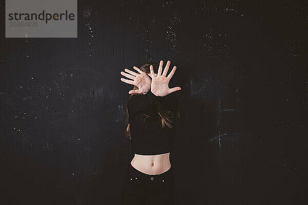 Girl with obscured face in front of black background