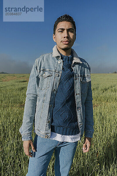 Man wearing denim jacket standing in meadow