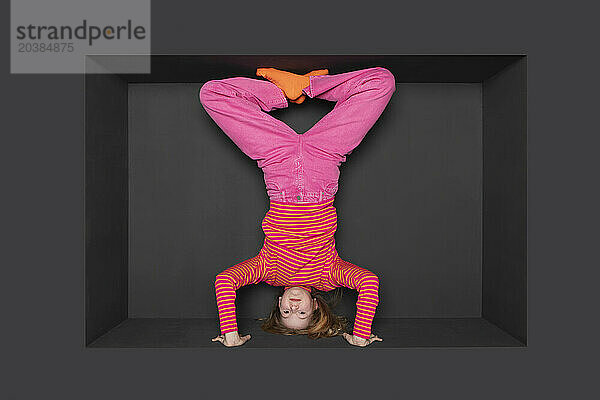 Teenager doing handstand over black background