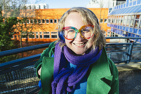 Smiling woman with colorful eyeglasses and headphones at sunny day