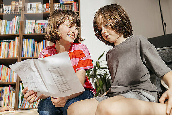 Smiling girl with boy reading instructions for assembling furniture at home