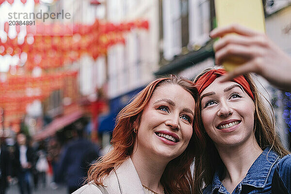 Smiling friends taking selfie through smart phone