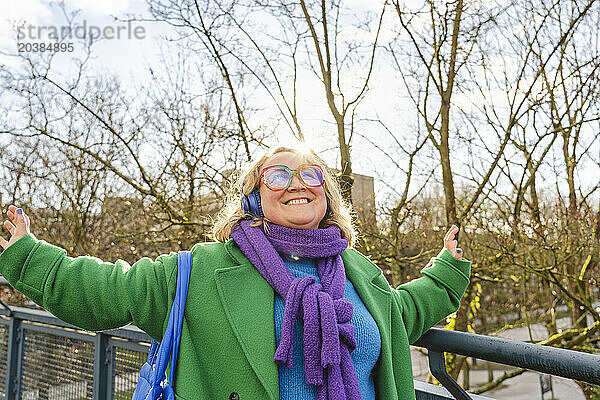 Cheerful woman enjoying listening to music near railing
