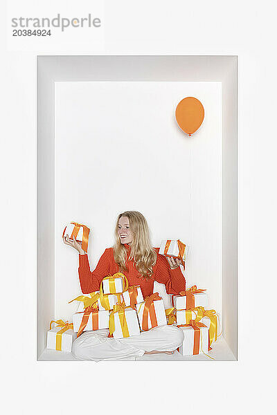 Teenage girl with gift boxes sitting in alcove against white background