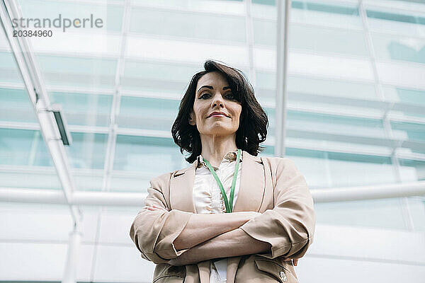 Smiling confident mature businesswoman wearing blazer standing with arms crossed