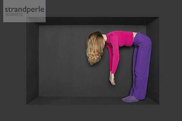 Blond teenage girl bending in alcove against black background