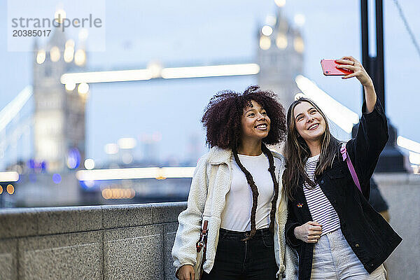 Happy friends taking selfie in front of tower bridge at London  England  UK