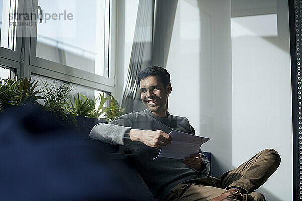 Smiling mature businessman sitting with documents in office