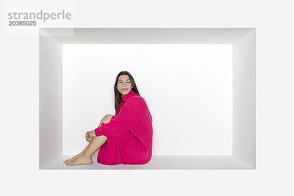 Teenage girl wearing pink dress sitting in alcove