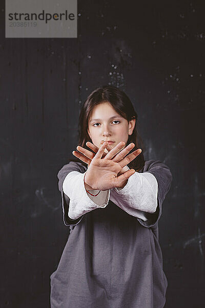 Girl showing stop gesture in front of black background