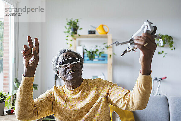 Senior man in VR glasses learning to operate drone at home