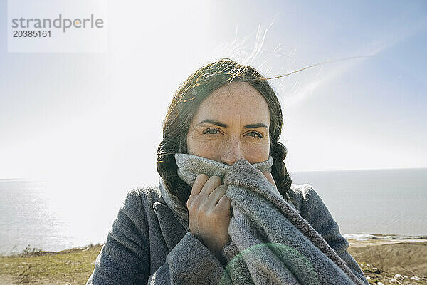Woman covering face with scarf at sunny day