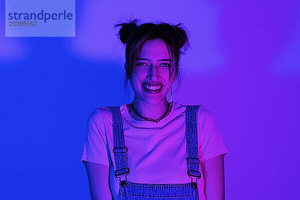 Illuminated happy young woman against colored background