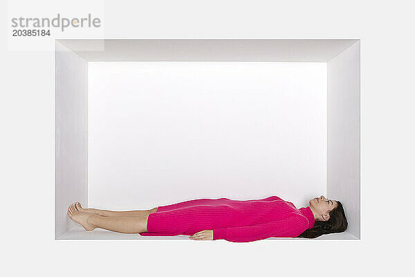Teenager lying down in alcove by white background