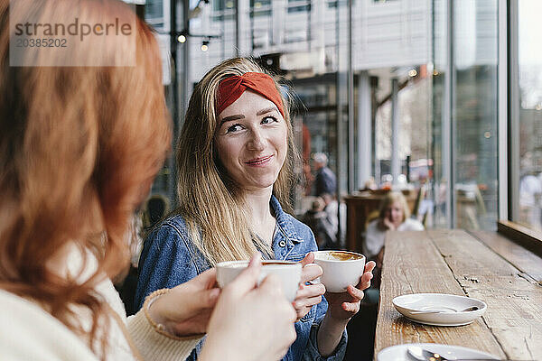 Smiling woman having coffee with friend in cafe