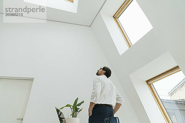 Businessman looking at skylight in minimalist office