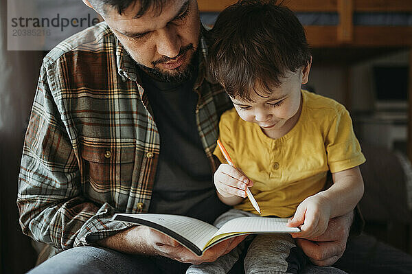 Father with son writing on notepad at home