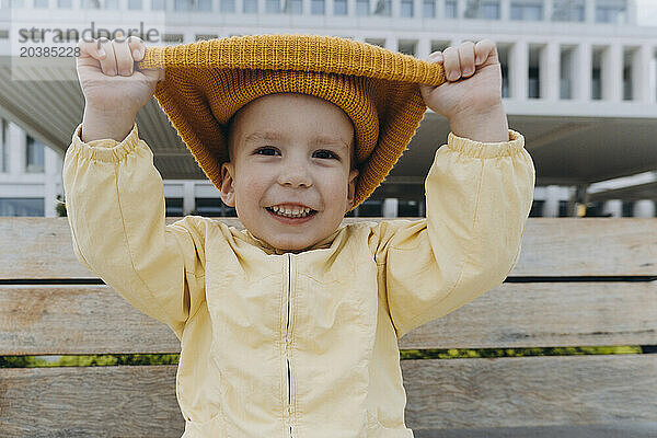Smiling boy pulling orange knit hat