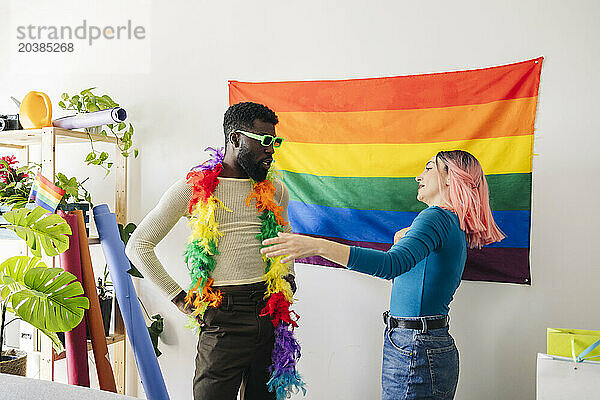 Woman talking with non-binary friend trying feather boa at home