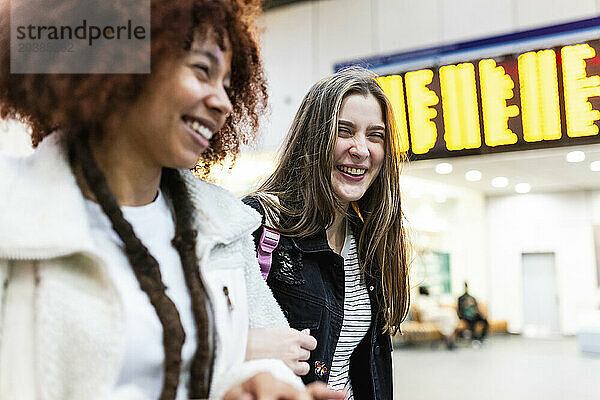 Cheerful young friends together at railroad station lobby