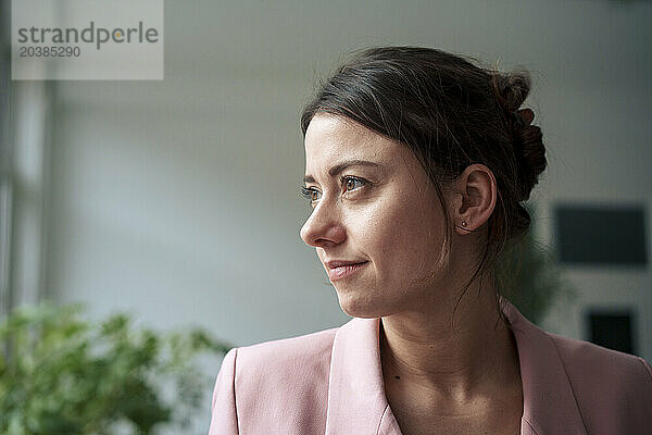 Thoughtful businesswoman wearing blazer looking away at home office