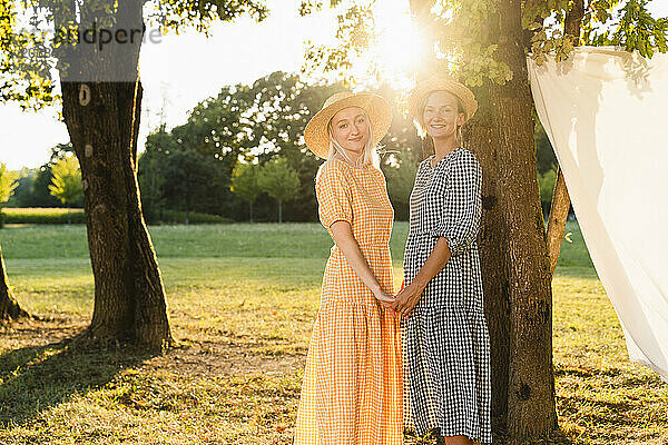 Friends holding hands standing in park