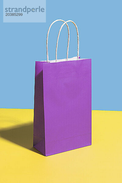 Purple paper shopping bag against colored background