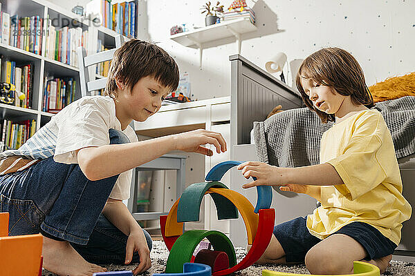 Boys playing with wooden multi colored toys at home