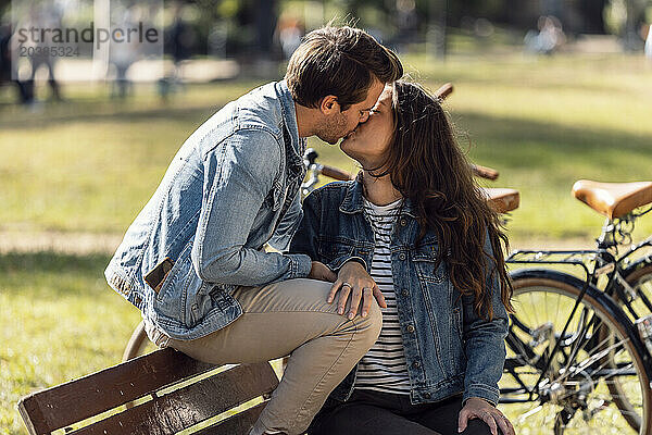 Affectionate couple kissing on bench at park