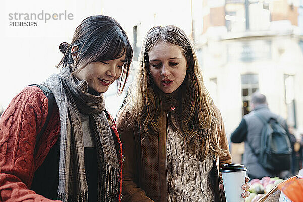 Sisters wearing warm clothes and talking in market