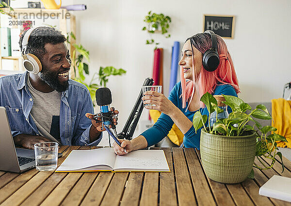 Happy influencers recording podcast together at desk