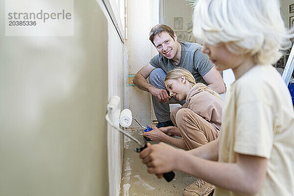 Children painting wall near father at home