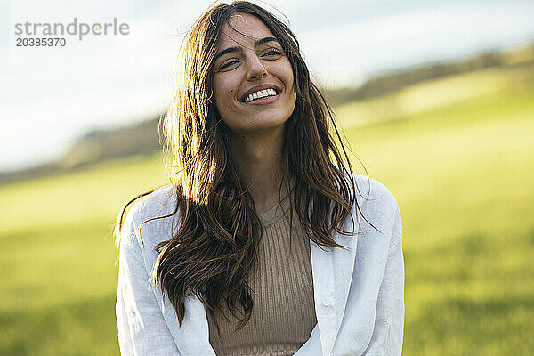 Happy beautiful young woman in field on sunny day