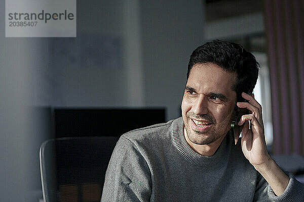 Happy businessman talking on mobile phone in office