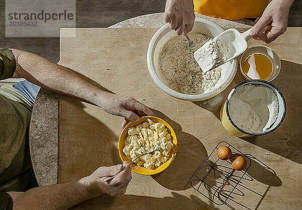 Senior couple preparing dough on table at home