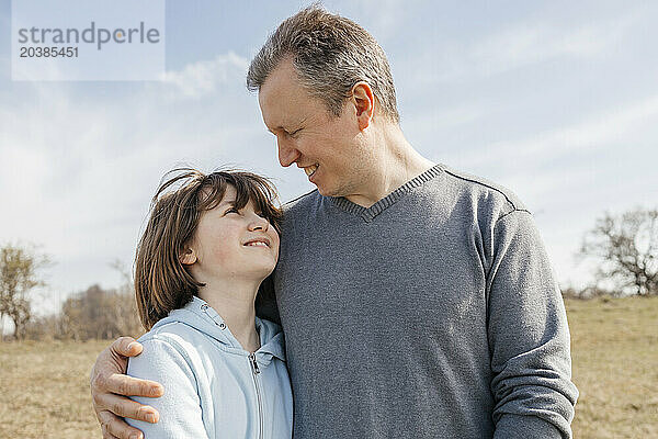 Smiling man embracing daughter at sunny day