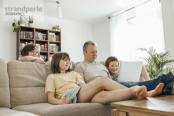 Father watching movie with children on laptop at home